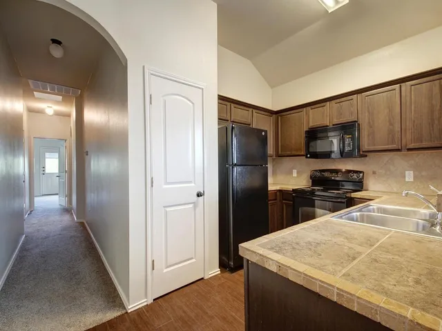 a kitchen with stainless steel appliances granite countertop a refrigerator a stove and a sink