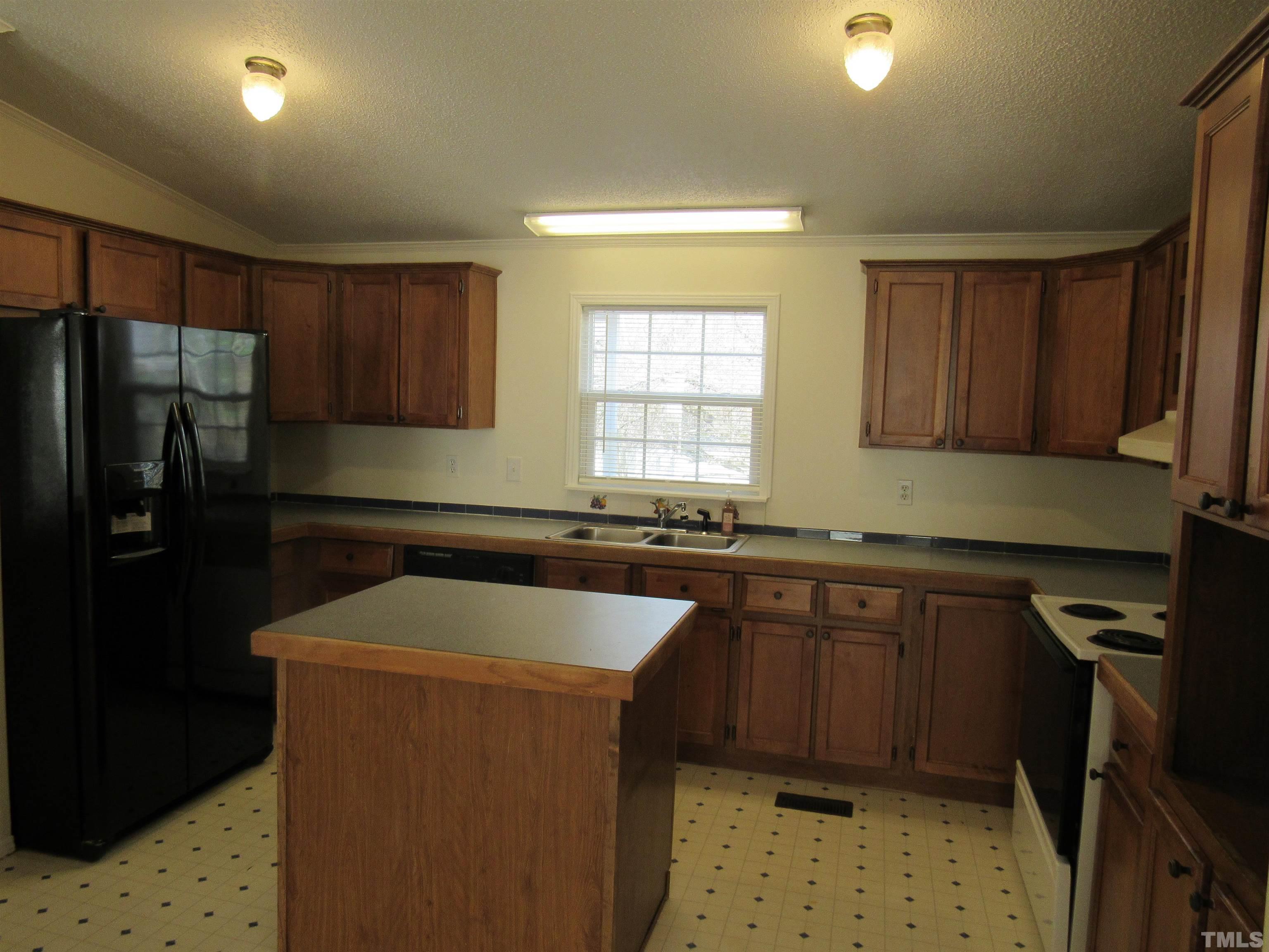 7816 Huff Farm Road Willow Spring, NC 27592 - Photo 7 of 25 a kitchen with a sink a stove a refrigerator and cabinets