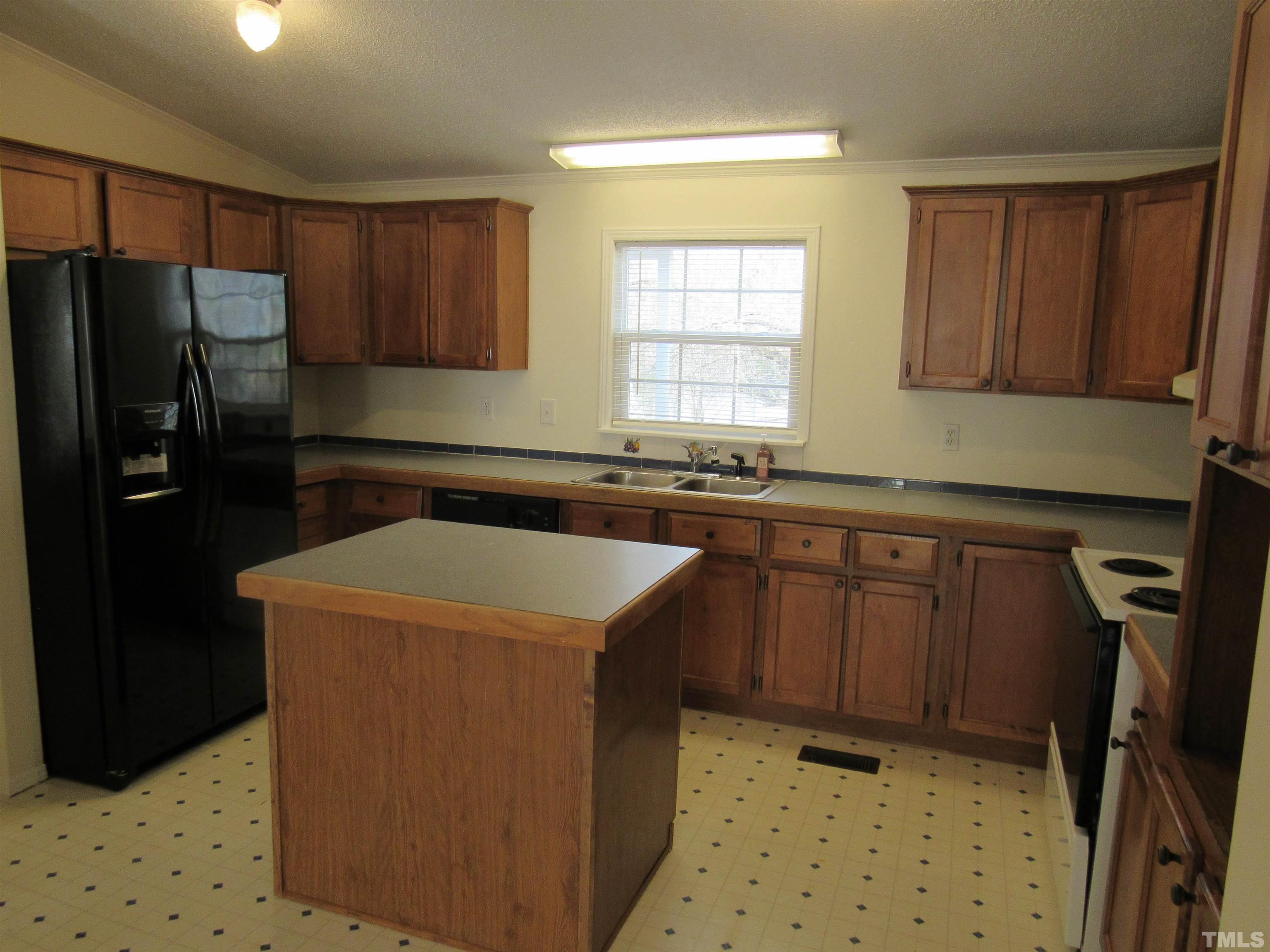 7816 Huff Farm Road Willow Spring, NC 27592 - Photo 8 of 25 a kitchen with a sink a refrigerator and wooden cabinets