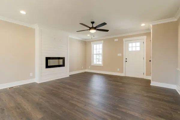 a view of an empty room with window and wooden floor