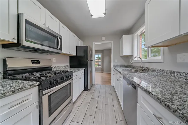 a kitchen with stainless steel appliances granite countertop a stove a sink and a microwave
