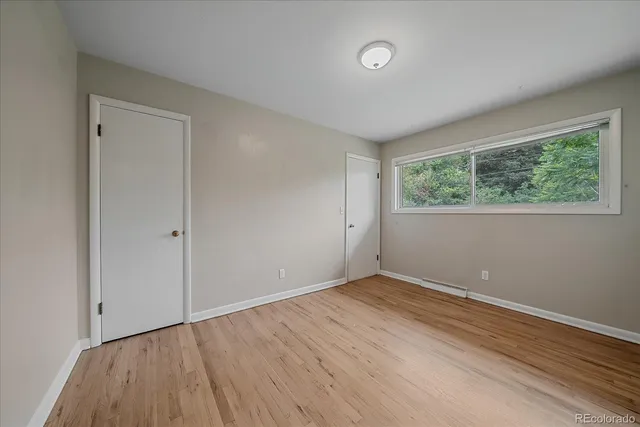 a view of an empty room with wooden floor and a window