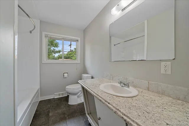 a bathroom with a granite countertop sink a toilet and a mirror