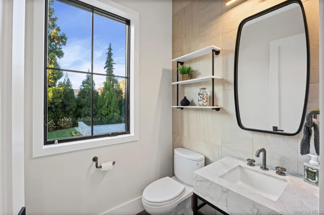 a bathroom with a toilet a sink a mirror and a window