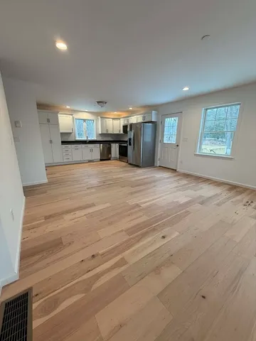 a view of empty room with wooden floor and window