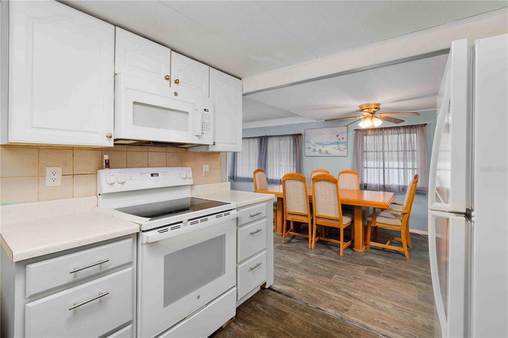 10399 67th Avenue North, Unit 4 St. Petersburg, FL 33708 - Photo 8 of 35 a kitchen with cabinets table stainless steel appliances and wooden floor