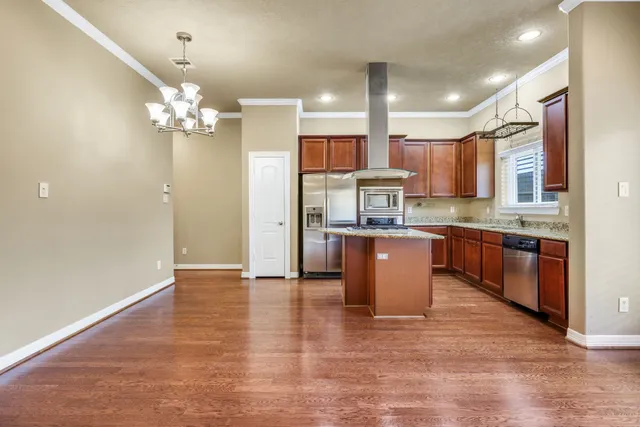 a large kitchen with stainless steel appliances kitchen island granite countertop a refrigerator a stove a sink and a microwave