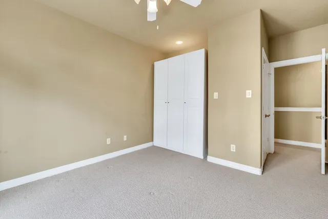 an empty room with closet and a chandelier fan