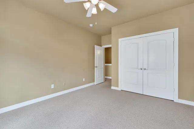 an empty room with a chandelier fan and closet area