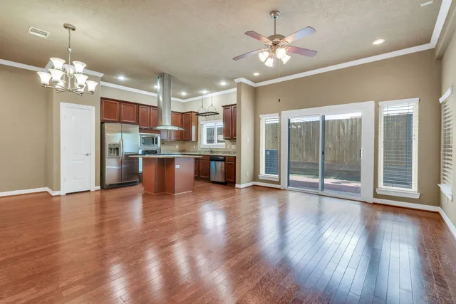 a view of a big room with wooden floor and a kitchen