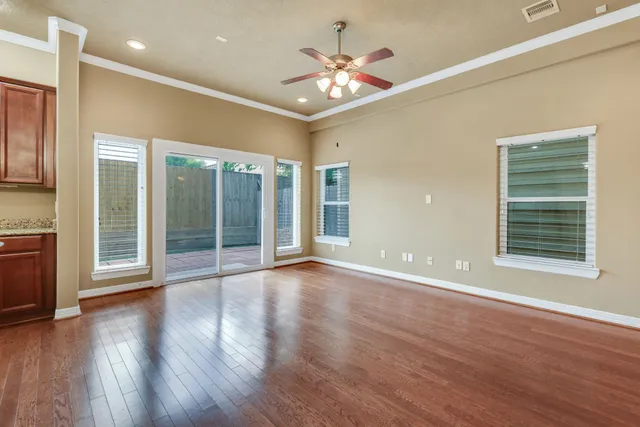 a view of an empty room with a window and wooden floor