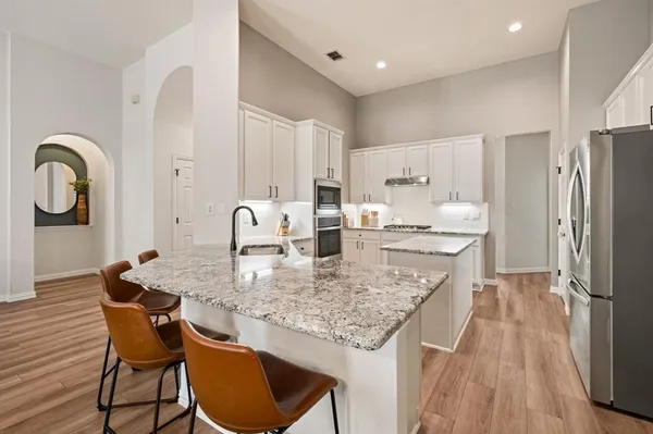 a kitchen with stainless steel appliances granite countertop a table chairs and a refrigerator