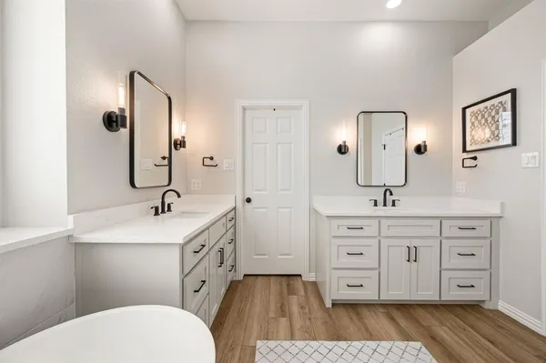 a spacious bathroom with a double vanity sink a toilet a mirror and