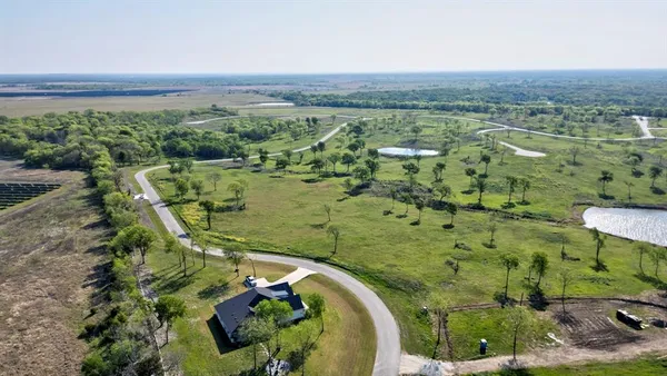 an aerial view of a residential houses with outdoor space and trees
