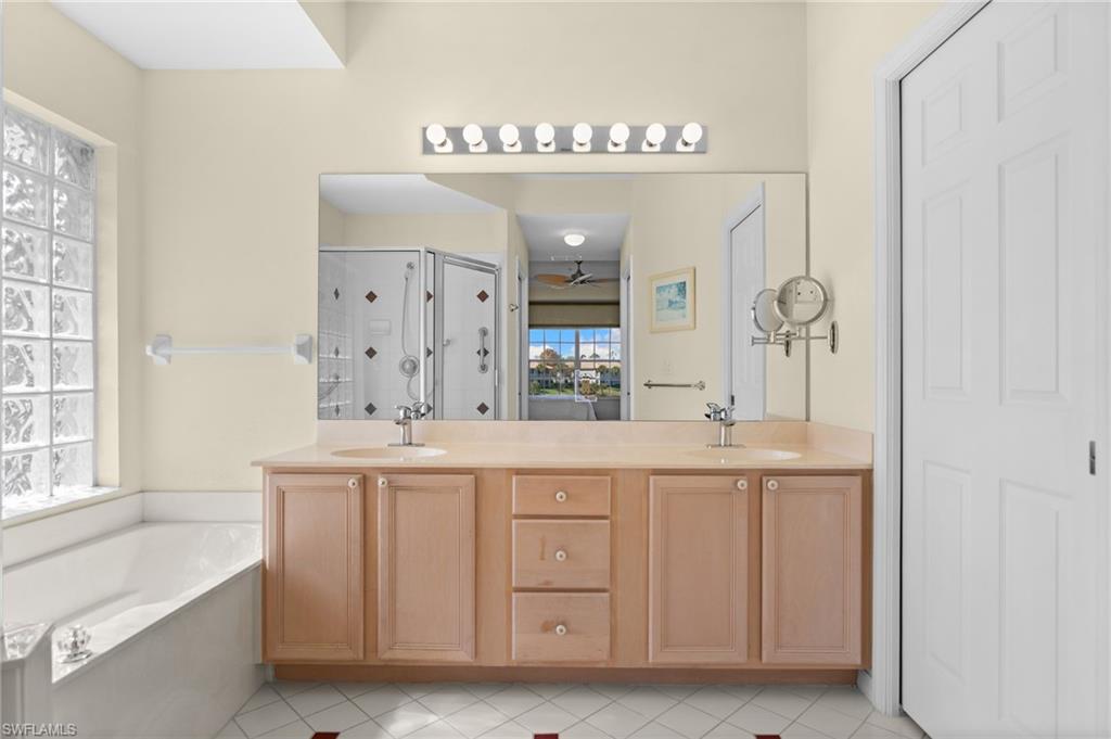 2255 Harmony Lane, Unit 204 Naples, FL 34109 - Photo 16 of 32 a spacious bathroom with a double vanity sink a mirror and a bathtub