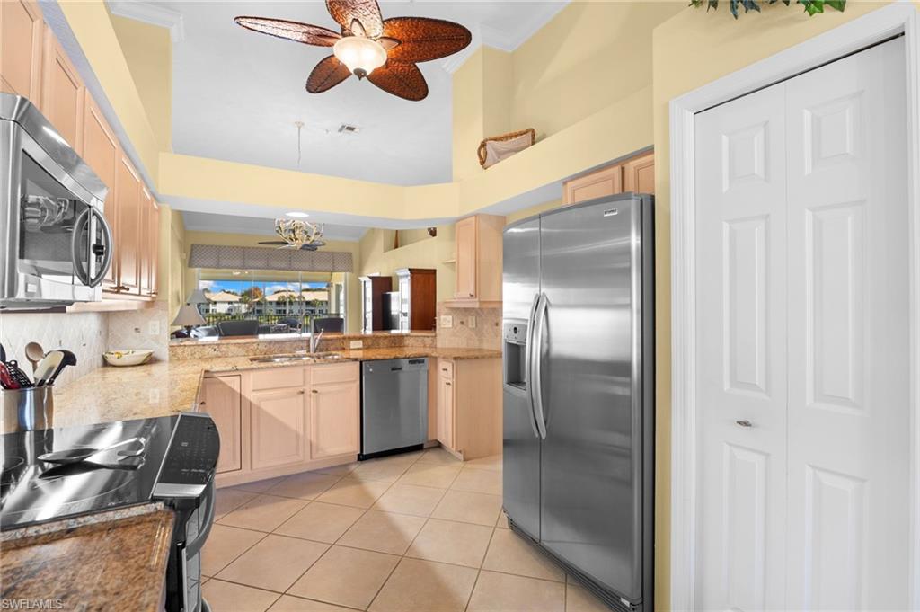2255 Harmony Lane, Unit 204 Naples, FL 34109 - Photo 5 of 32 a kitchen with granite countertop stainless steel appliances a stove and a refrigerator