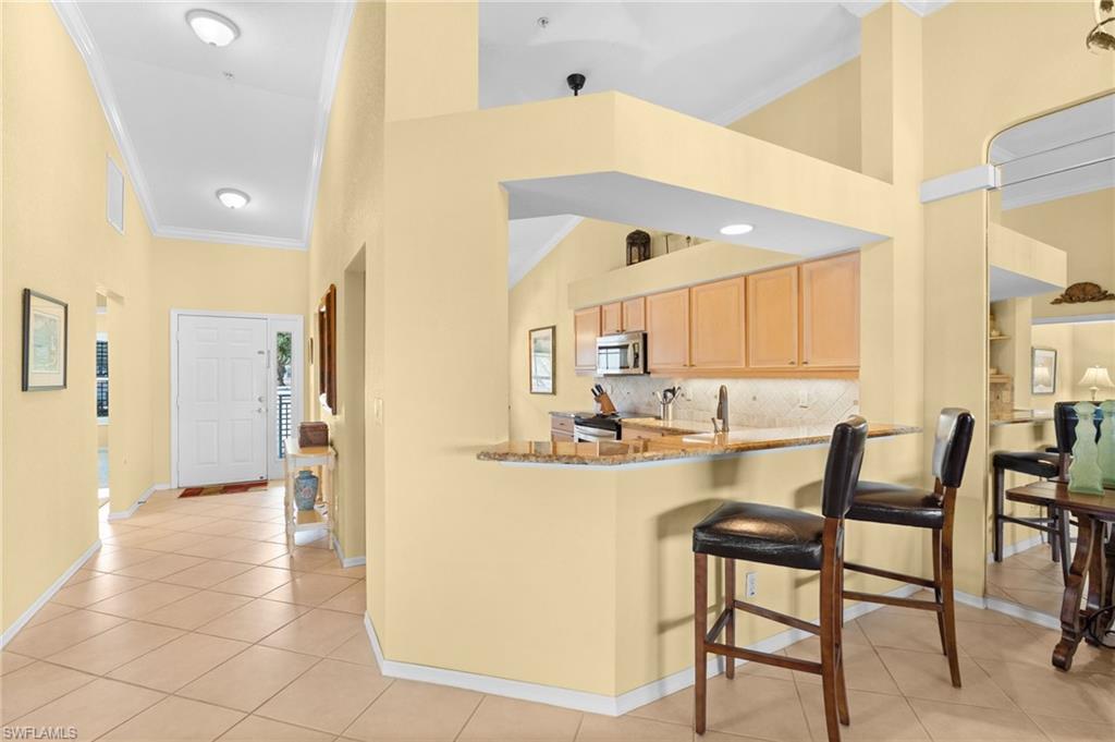2255 Harmony Lane, Unit 204 Naples, FL 34109 - Photo 8 of 32 a kitchen with stainless steel appliances kitchen island granite countertop a refrigerator and cabinets