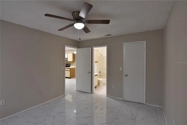 an empty room with a window and a fan