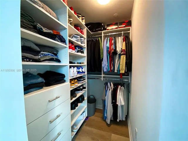 a view of walk in closet with clothes and shoes