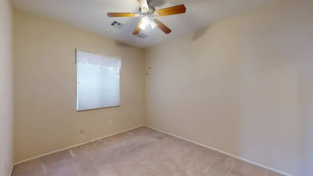 a view of an empty room with a ceiling fan and a window