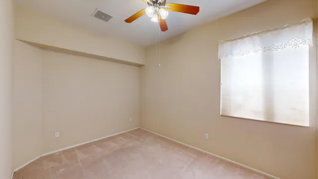 an empty room with closet and a chandelier fan