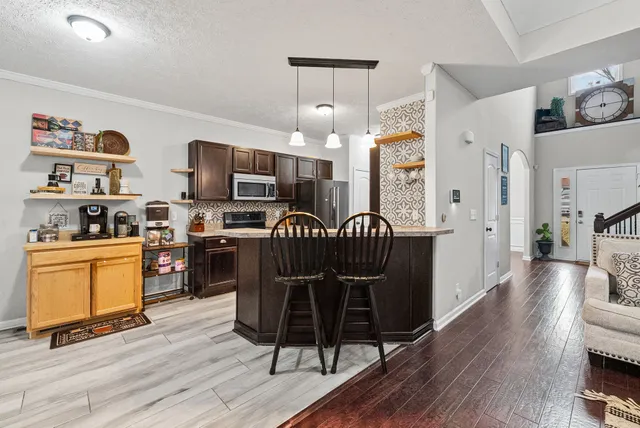 a kitchen with stainless steel appliances granite countertop a refrigerator a stove top oven a sink dishwasher and white cabinets with wooden floor