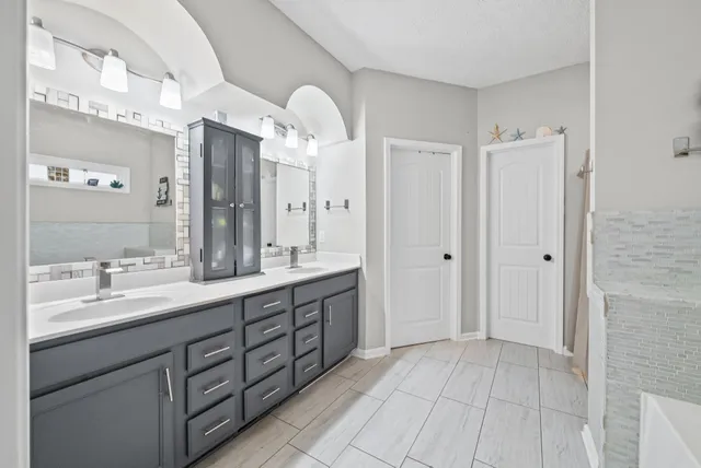 a spacious bathroom with a double vanity sink a mirror and a shower