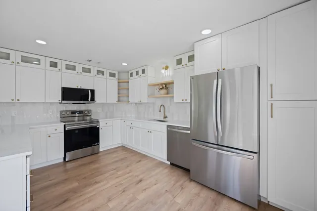 a kitchen with granite countertop a sink stainless steel appliances and white cabinets