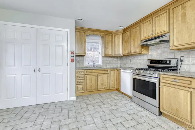 a kitchen with stainless steel appliances granite countertop a stove a sink and a refrigerator