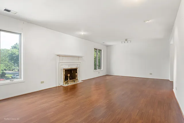 an empty room with wooden floor fireplace and windows