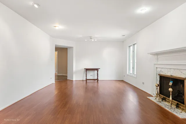 a view of an empty room with wooden floor and a fireplace