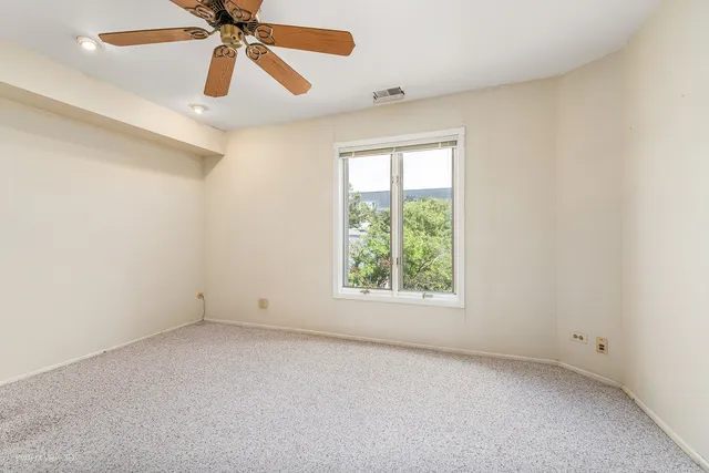 an empty room with a window and a fan