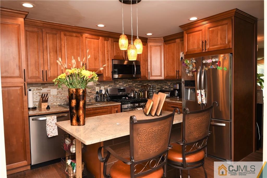 171 Salem Road North Brunswick, NJ 08902 - Photo 3 of 44 a kitchen with stainless steel appliances kitchen island granite countertop a refrigerator a stove a sink dishwasher and a dining table with wooden floor