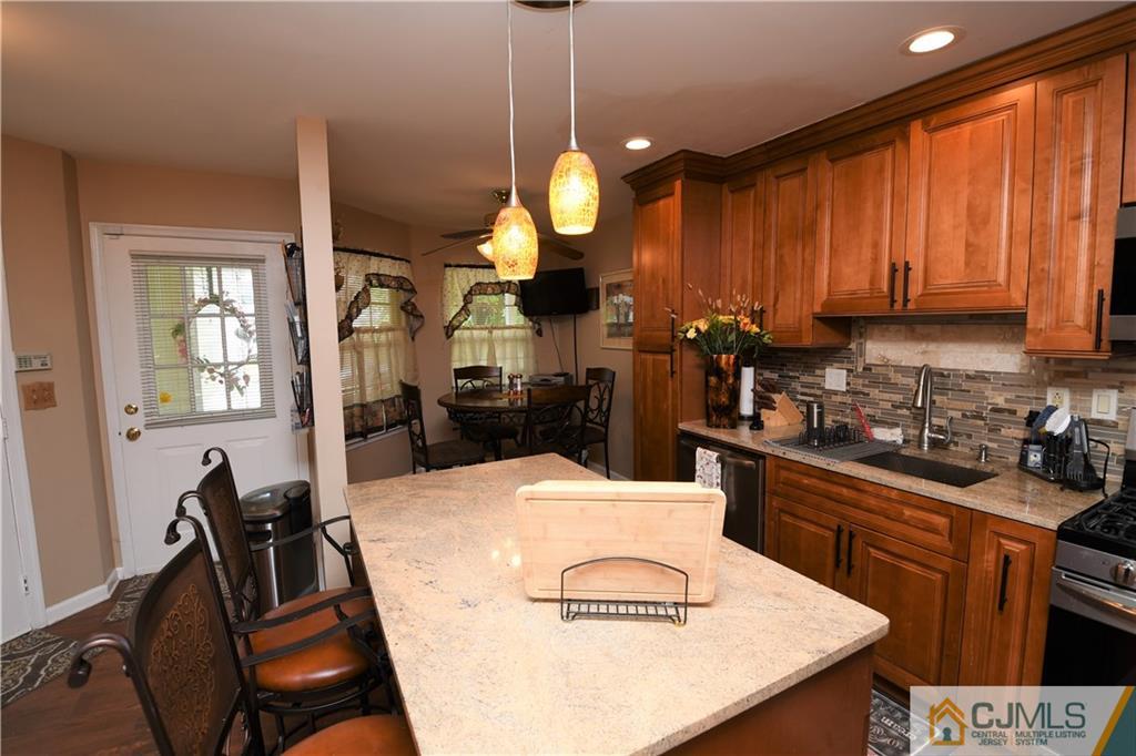 171 Salem Road North Brunswick, NJ 08902 - Photo 4 of 44 a kitchen with granite countertop a stove a oven a dining table and chairs with wooden floor
