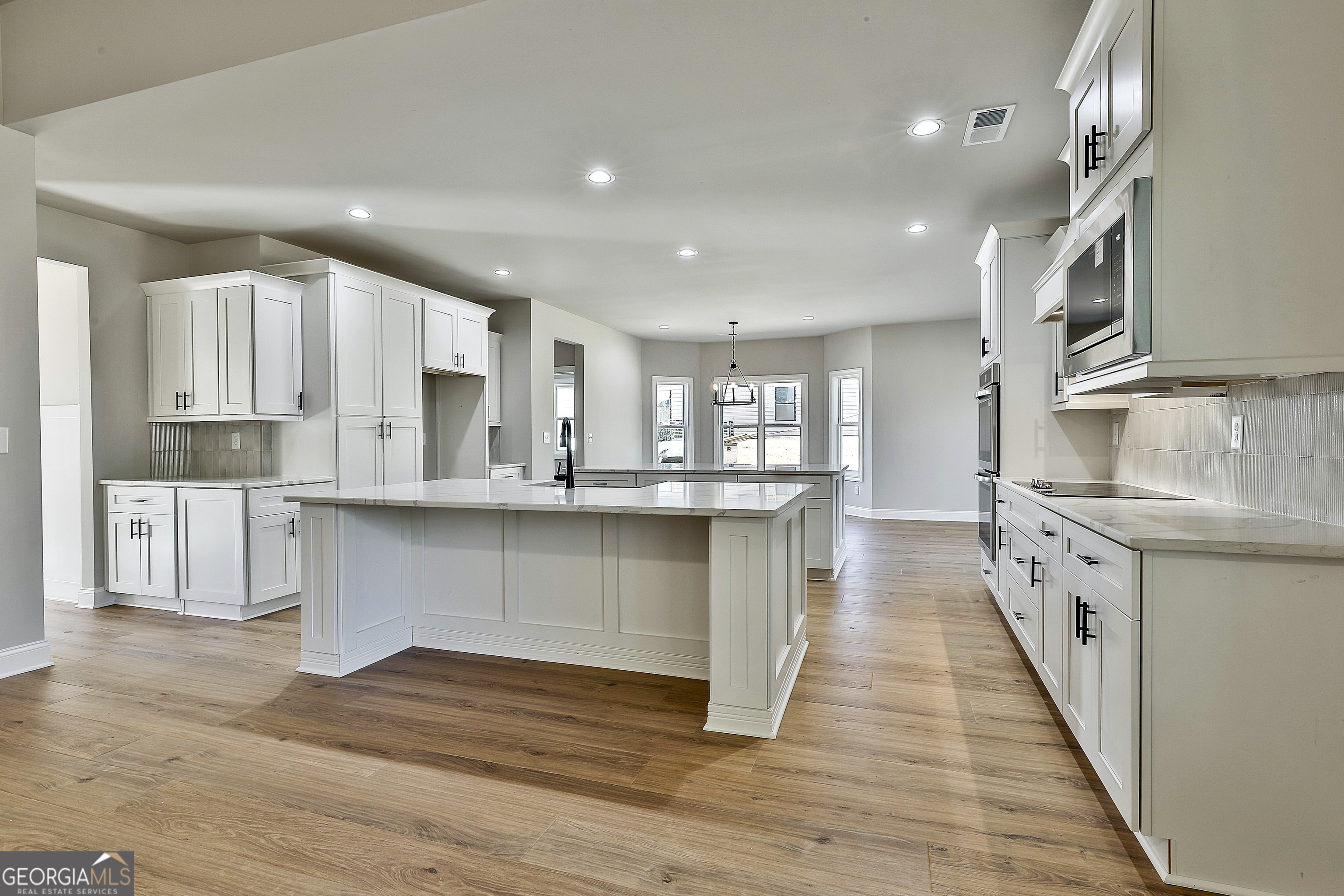 174 Tattersall Way, Unit 5100 Senoia, GA 30276 - Photo 14 of 40 a kitchen with stainless steel appliances granite countertop a refrigerator a sink dishwasher and white cabinets with wooden floor