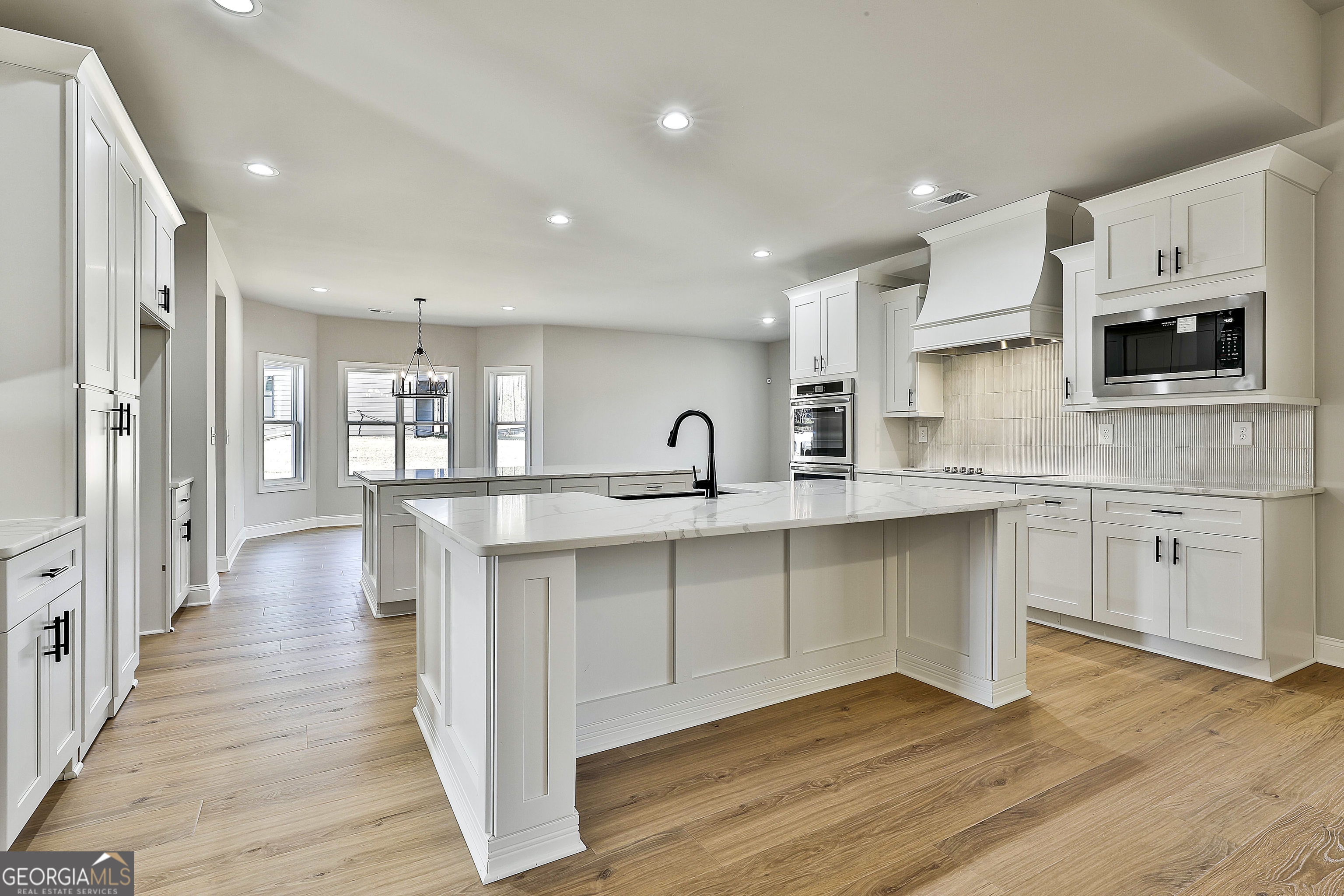 174 Tattersall Way, Unit 5100 Senoia, GA 30276 - Photo 16 of 40 a kitchen with stainless steel appliances a stove top oven a sink a refrigerator white cabinets and wooden floor