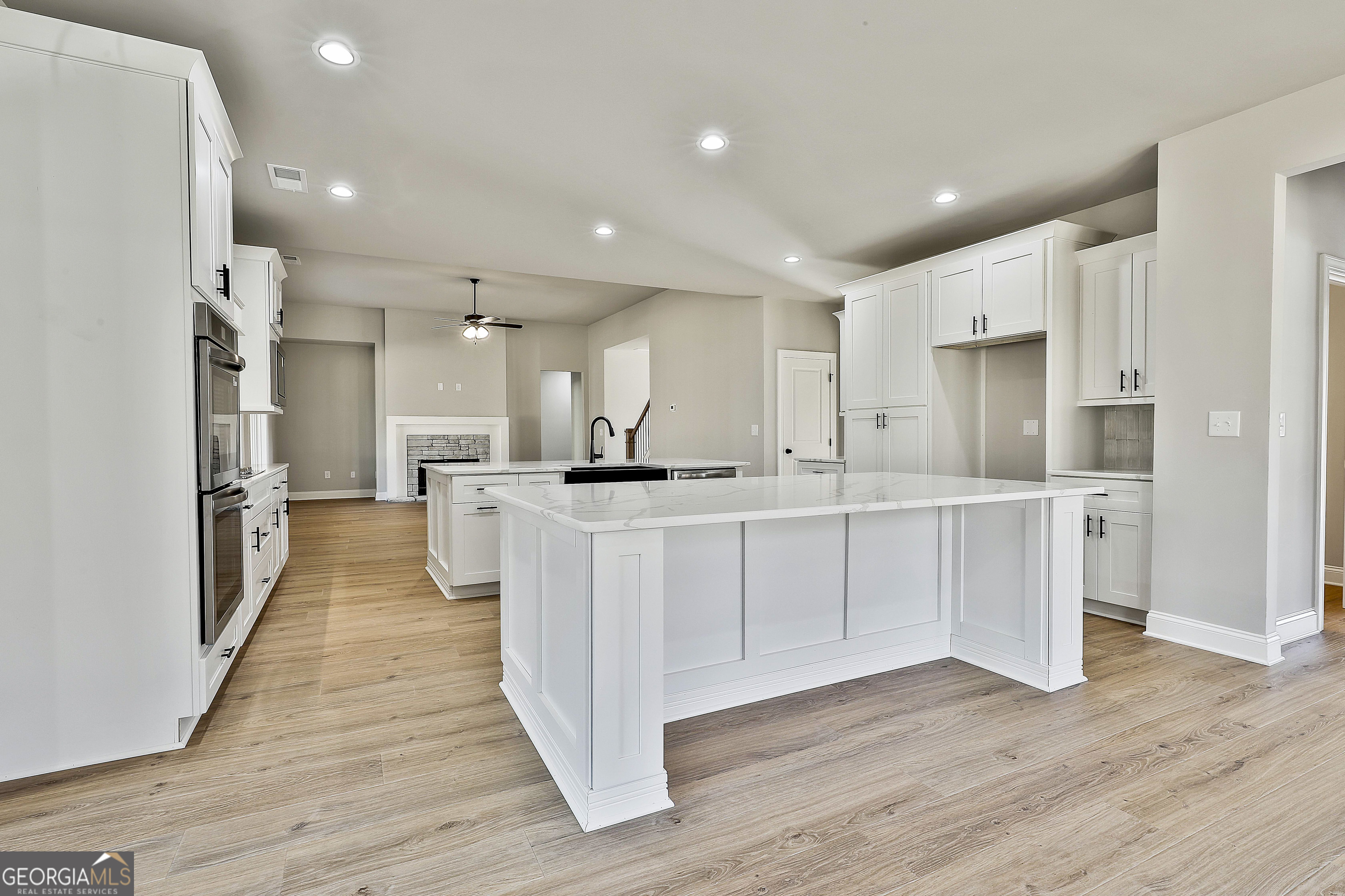 174 Tattersall Way, Unit 5100 Senoia, GA 30276 - Photo 26 of 40 a kitchen with stainless steel appliances kitchen island wooden floors refrigerator and white cabinets