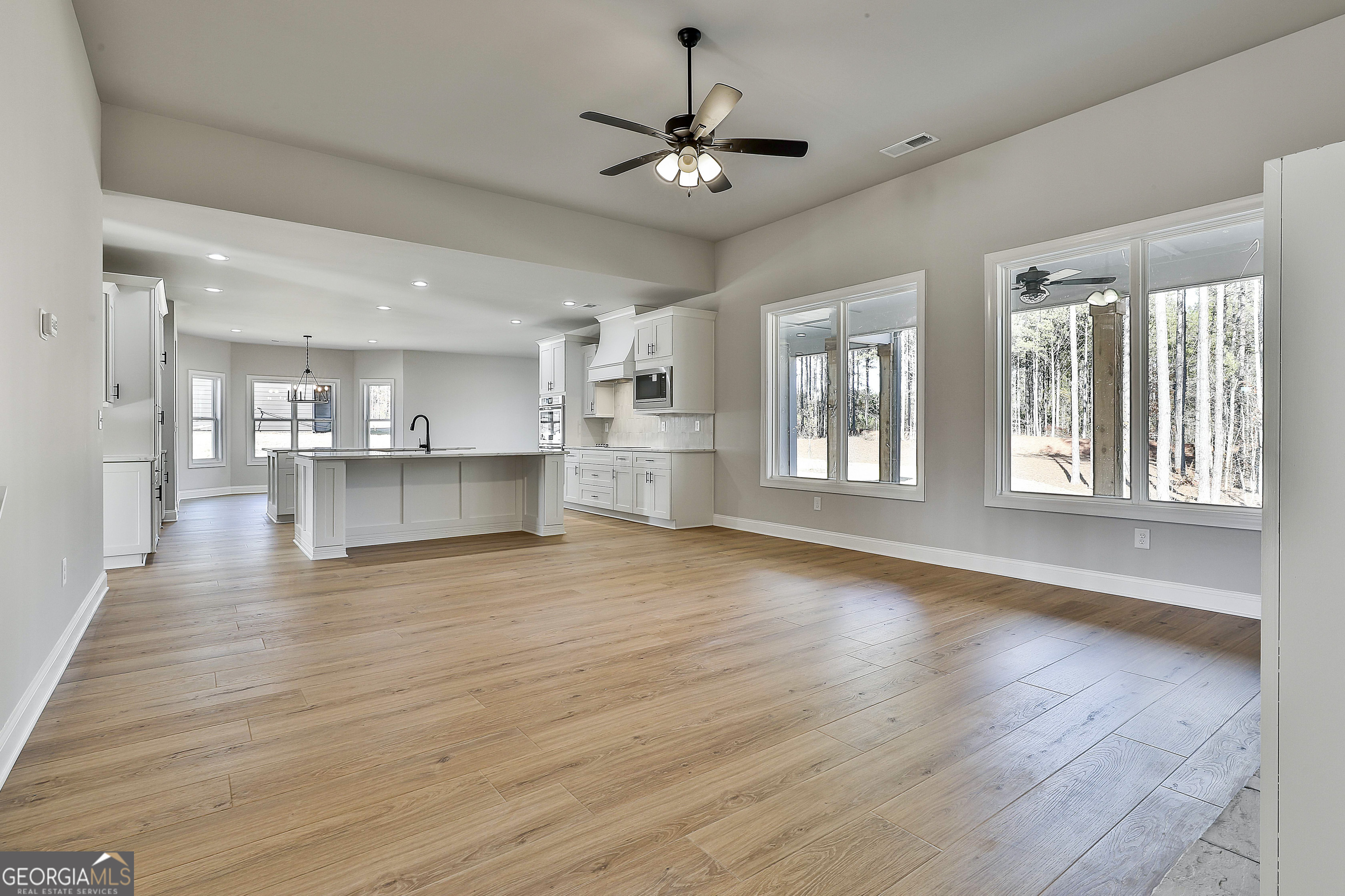174 Tattersall Way, Unit 5100 Senoia, GA 30276 - Photo 9 of 40 a view of an empty room with a kitchen and wooden floor