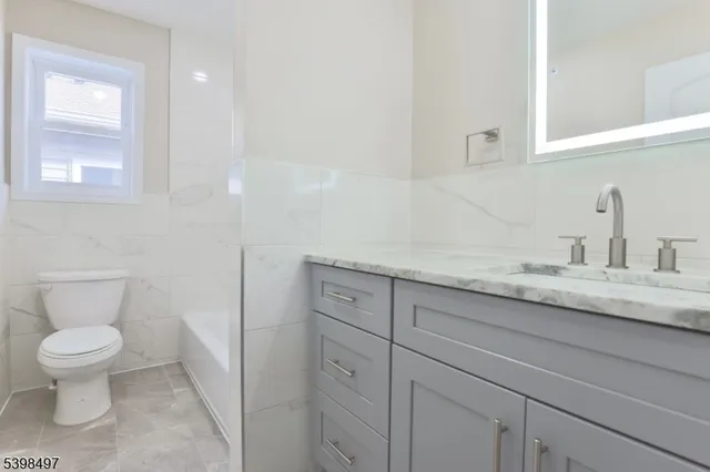 a bathroom with a granite countertop toilet sink and mirror