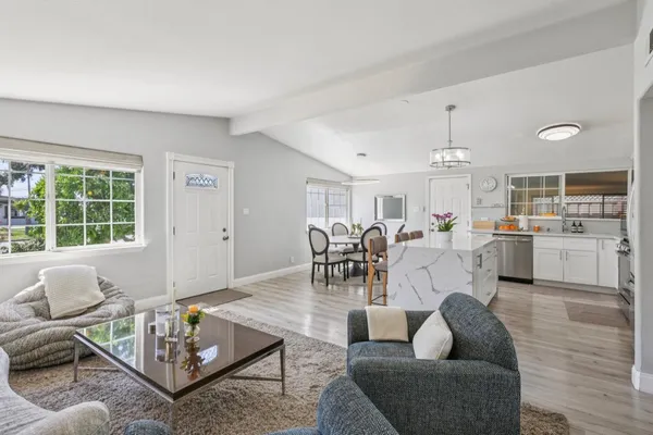 a kitchen with stainless steel appliances kitchen island granite countertop a stove a sink dishwasher a refrigerator white cabinets and wooden floor