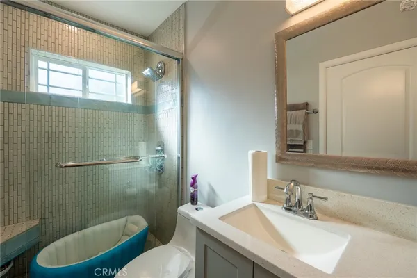 a bathroom with a sink a toilet a mirror and shower