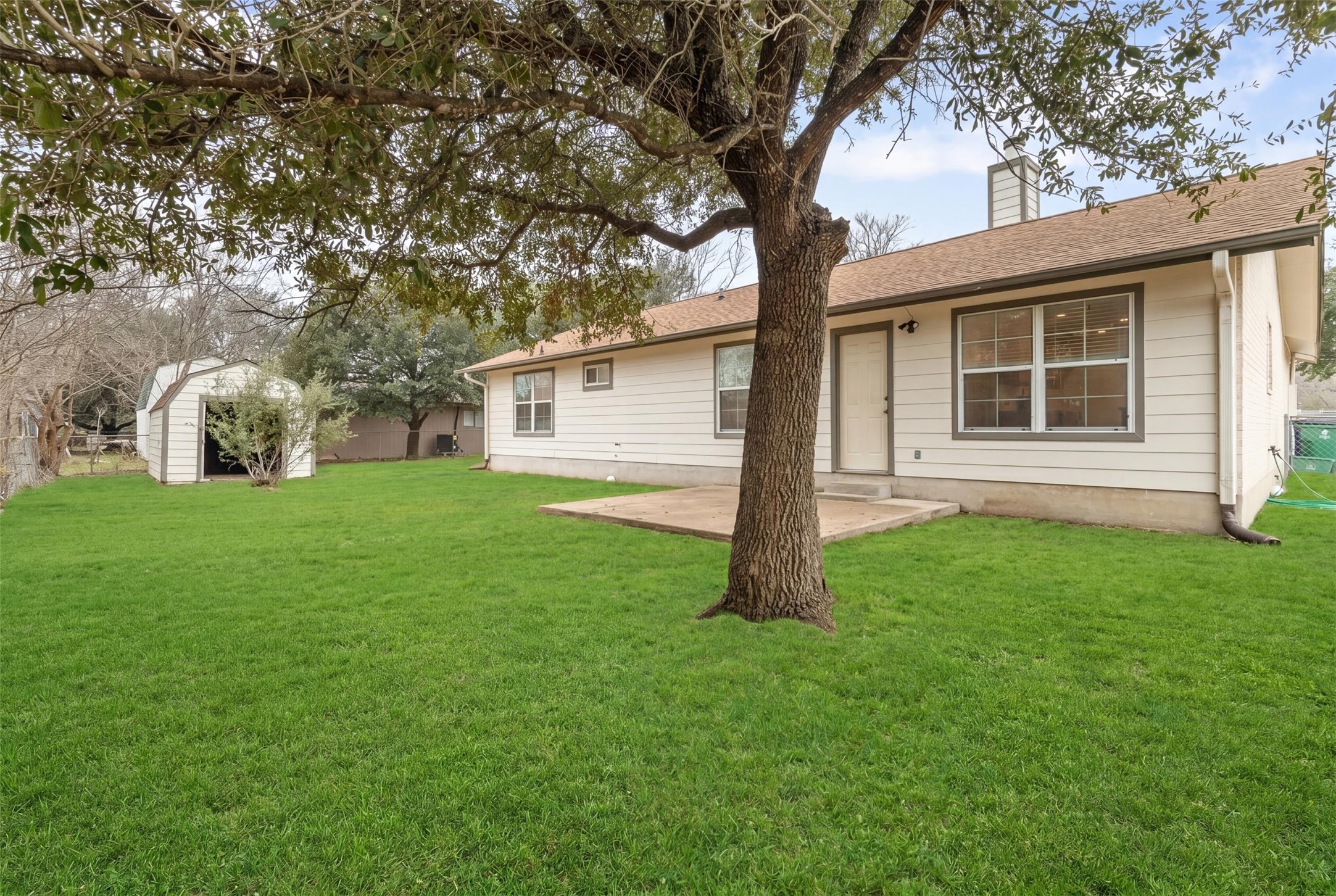 2602 Peach Tree Lane Cedar Park, TX 78613 - Photo 14 of 14 Expansive grassy backyard featuring a large mature tree, a concrete patio, and a separate storage shed