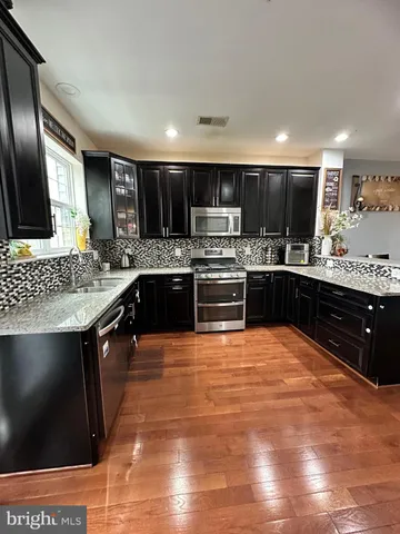 a large kitchen with stainless steel appliances kitchen island granite countertop a sink counter space and cabinets