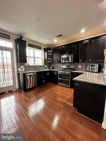 a kitchen with stainless steel appliances kitchen island granite countertop a stove a sink and a microwave