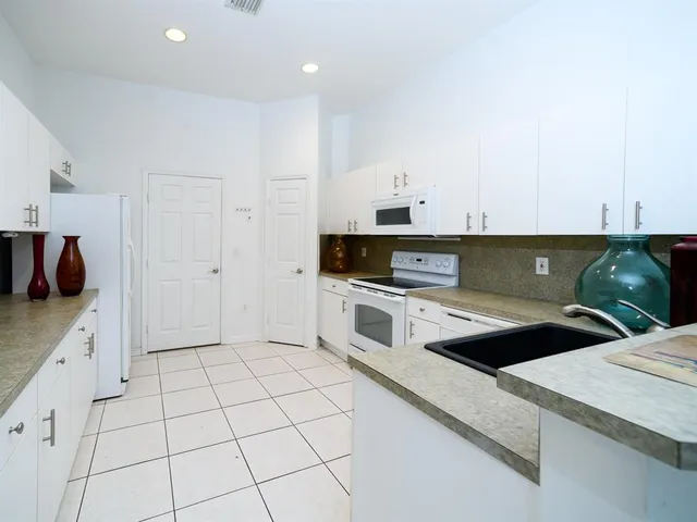 a kitchen with granite countertop white cabinets and white appliances