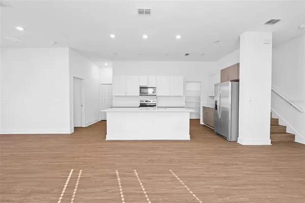 a large white kitchen with kitchen island a stove a refrigerator a sink and a cabinets