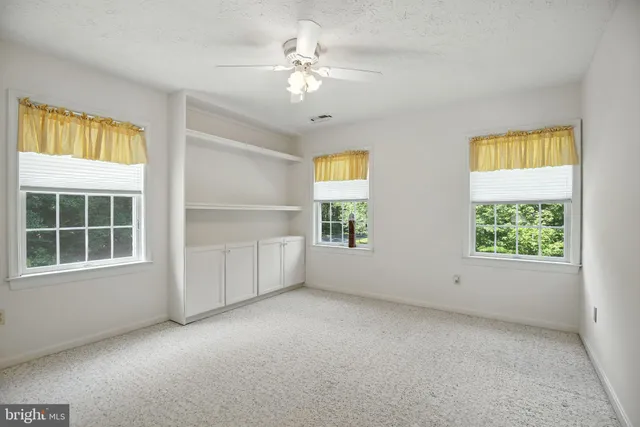 an empty room with windows and ceiling fan