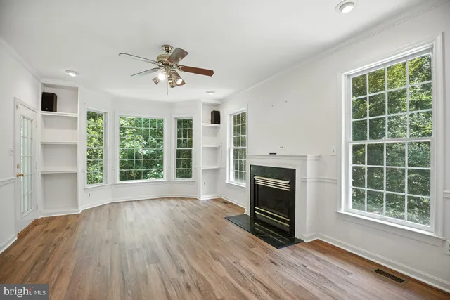 an empty room with windows fireplace and wooden floor