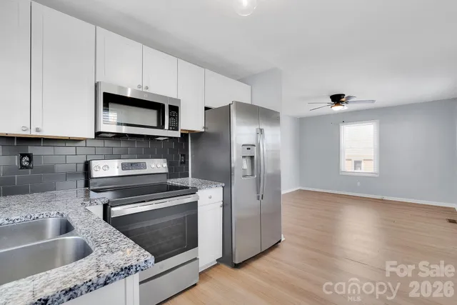 a kitchen with granite countertop a sink cabinets and stainless steel appliances
