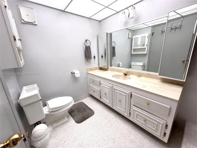 a bathroom with a granite countertop toilet sink and mirror